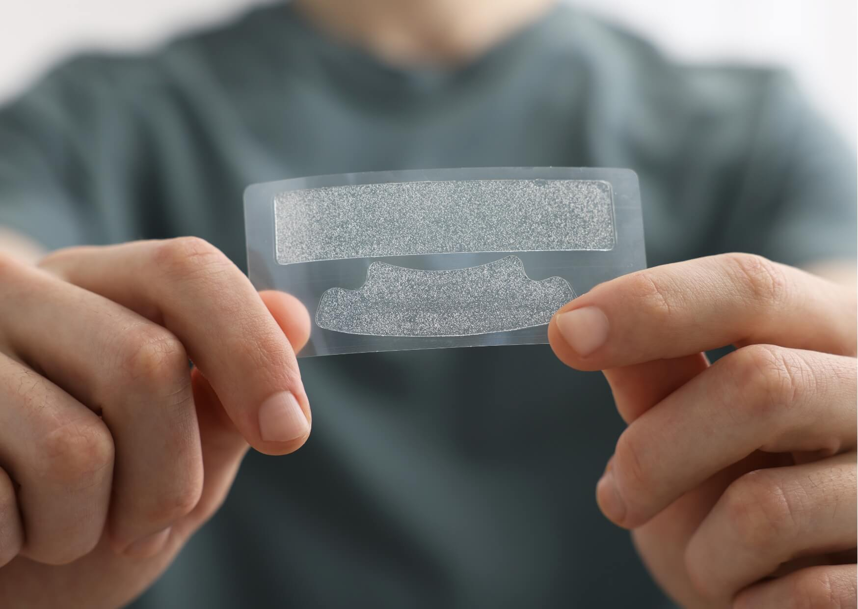 Person holding over-the-counter teeth whitening strips before application, illustrating the effectiveness of teeth whitening strips for removing surface stains.