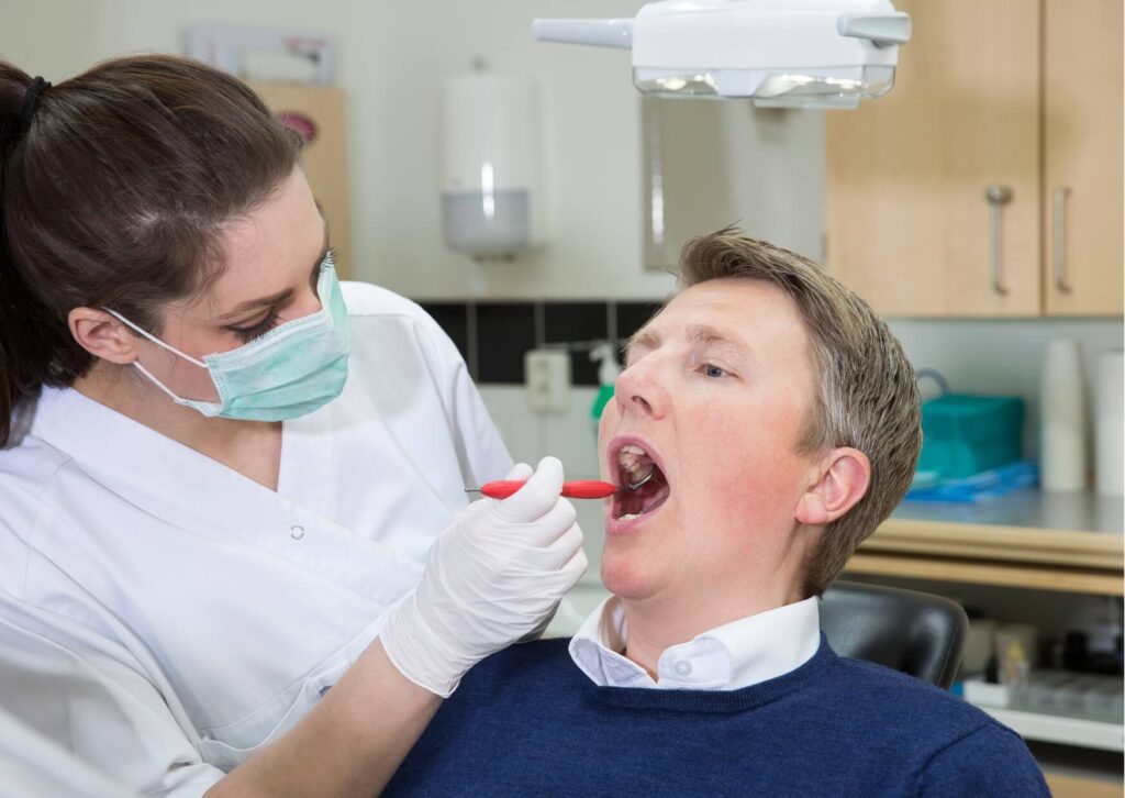 Dentist examining a patient's worn teeth during a consultation about fixing grinded teeth with restorative dental treatment.