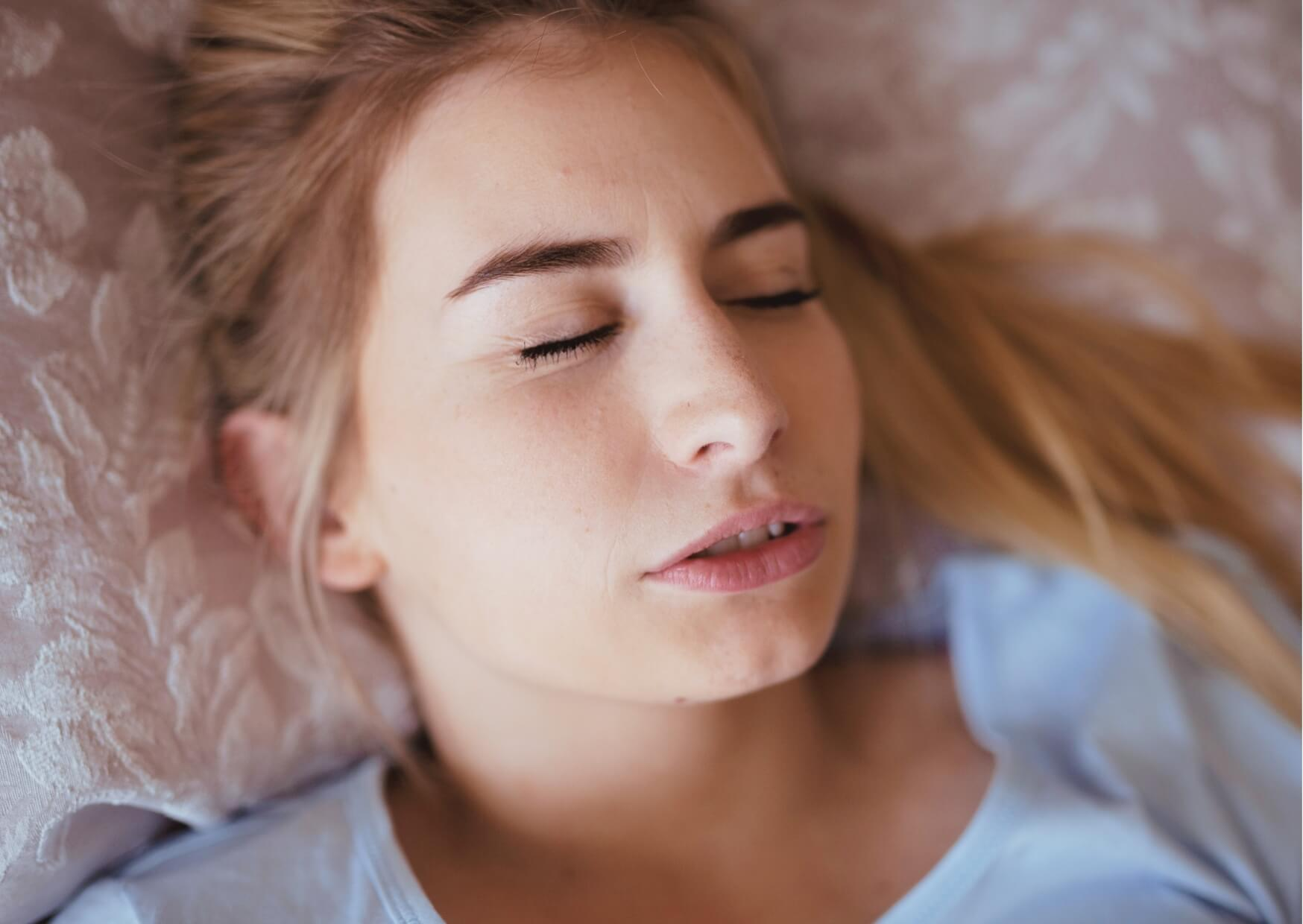Woman sleeping peacefully at night, highlighting the effects of teeth grinding and the need for treatment to repair worn teeth.