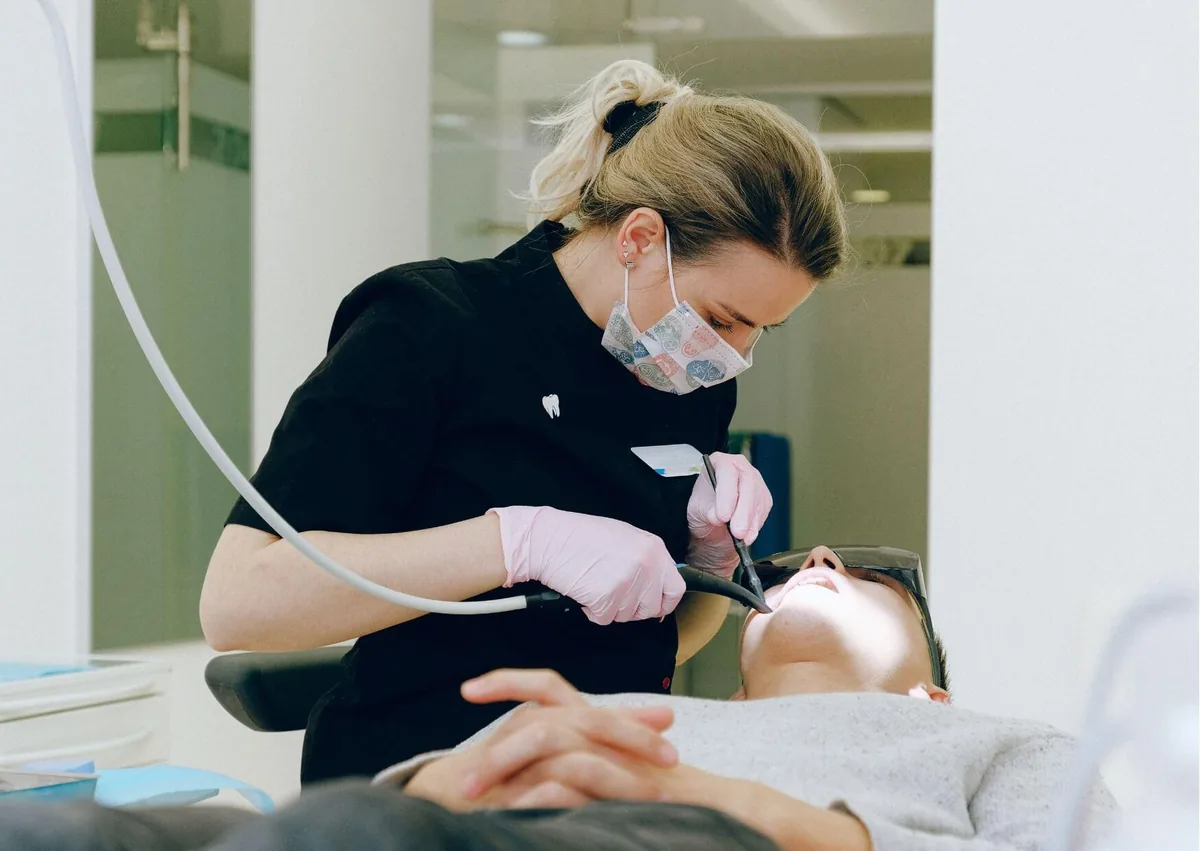 Dental professional cleaning a patient&rsquo;s teeth as part of routine care for preventing cavities.