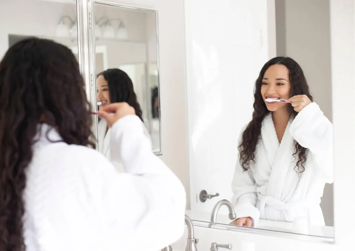 Woman brushing her teeth as part of daily oral care to help maintain dental crowns.