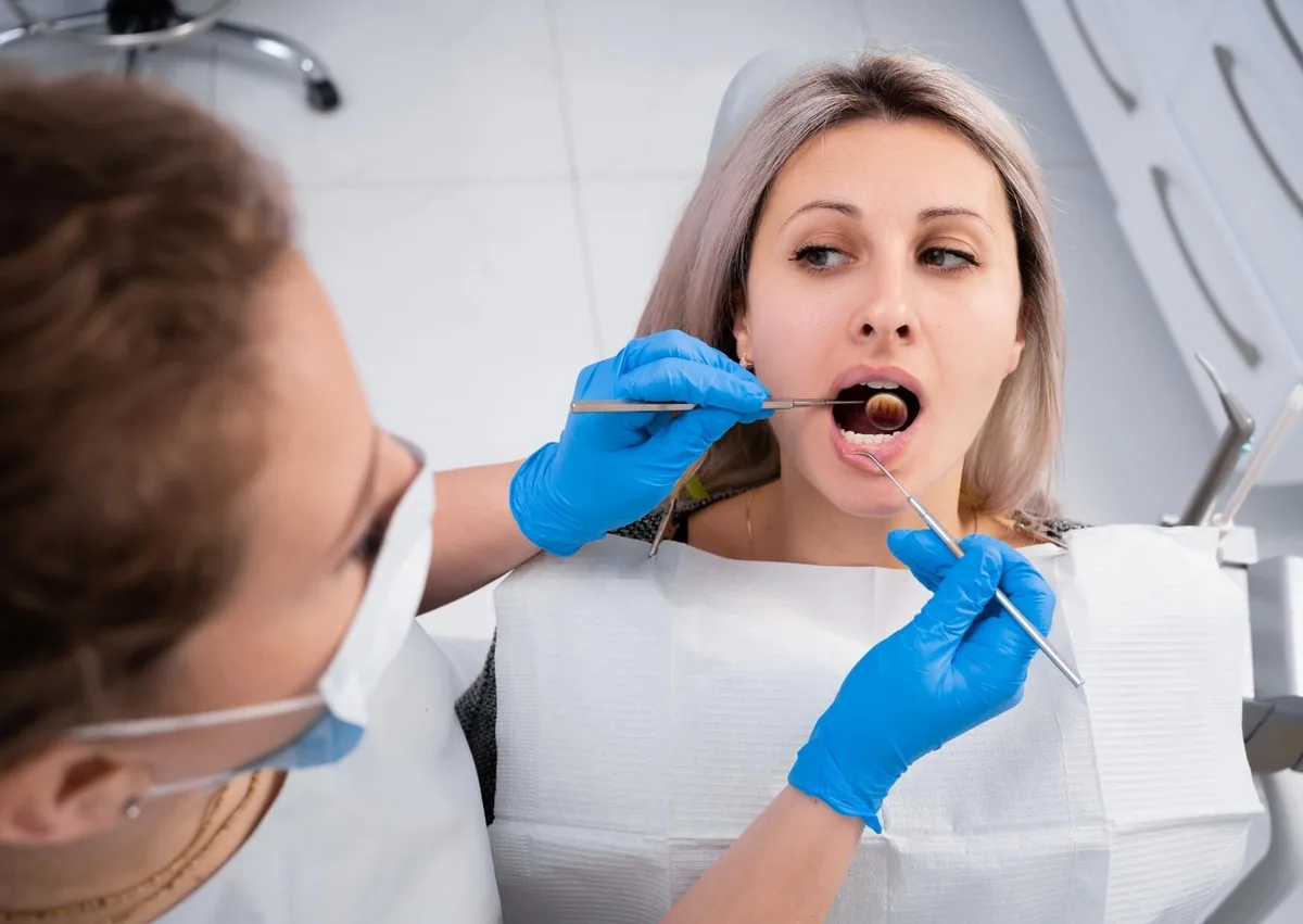 Dentist examining a patient’s mouth to evaluate a canker sore and its healing progress.