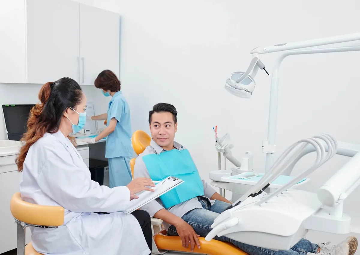 Dentist discussing the tooth implant timeline and treatment stages with a patient during a consultation.