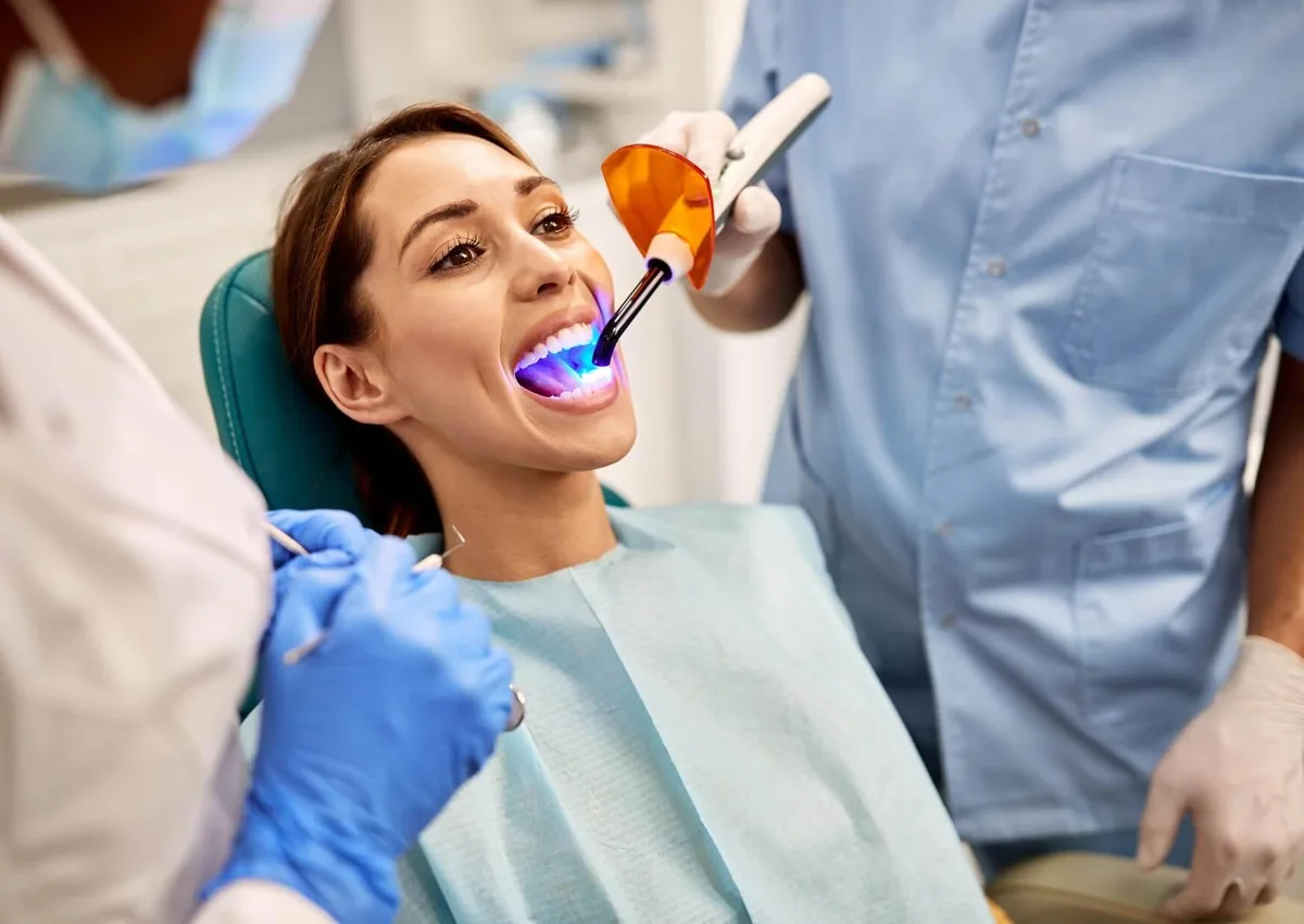 Patient receiving teeth bonding treatment with dental resin cured using a special light.